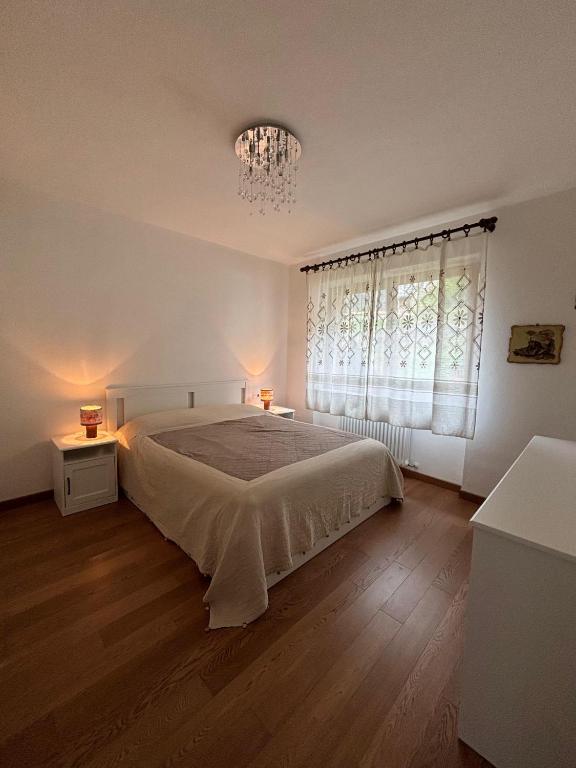 a bedroom with a bed and a window with a chandelier at Casa Latemar in Moena