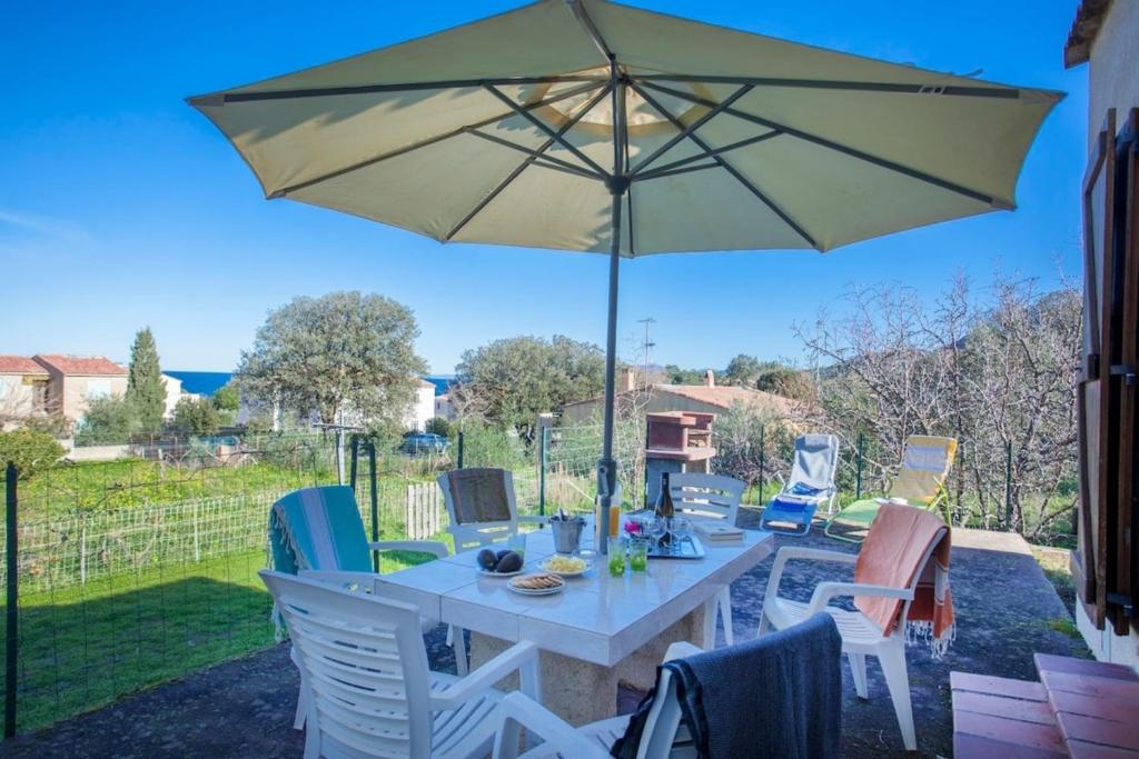 une table et des chaises avec un parasol sur une terrasse dans l'établissement Domaine Bollaccia - Casa Ostriconi, à Monticello