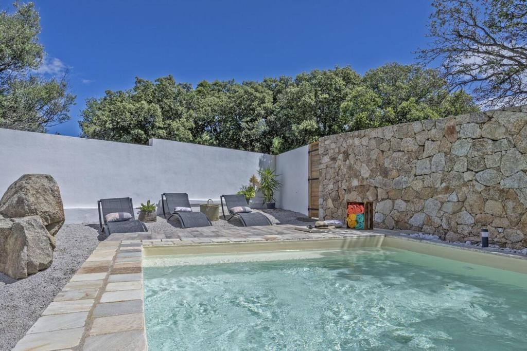a swimming pool with chairs and a stone wall at E Case D’Olivia Casa 1 in Monticello