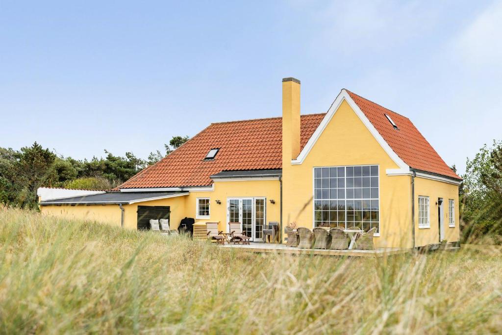 a yellow house with a red roof on a field at Historic House Near Råbjerg Mile And North Sea in Kandestederne