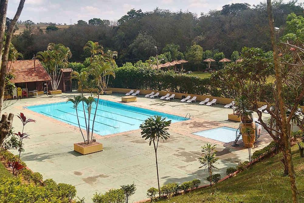 a swimming pool with lounge chairs in a resort at Chalé frente para o lago - Camping Carrion in Itu