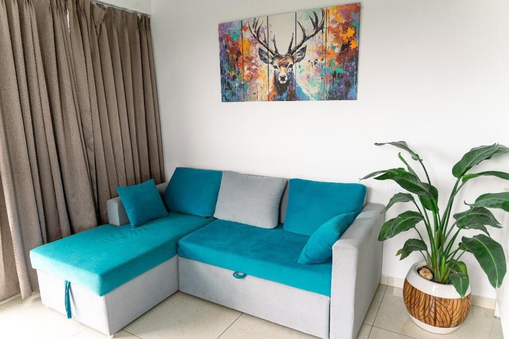 a living room with a blue couch and a painting at Anandam Luxury Hill View 1BHK in Pune in Pune