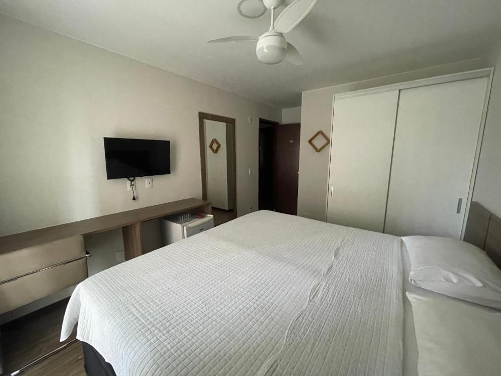 a bedroom with a white bed and a flat screen tv at Via premiere in Rio de Janeiro