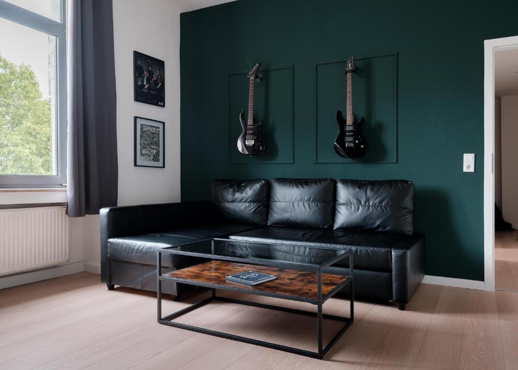 a living room with a black couch and two guitars on the wall at Rock City Apartments Room 555 in Essen