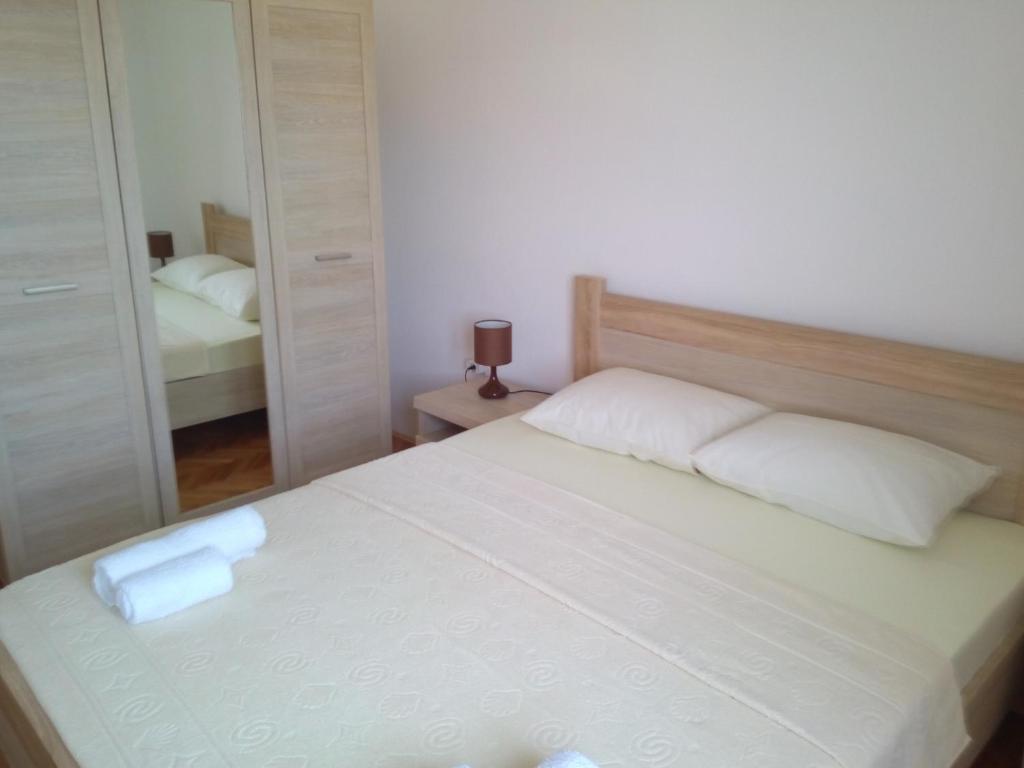 a bedroom with a white bed and a mirror at Sun Apartments in Tivat