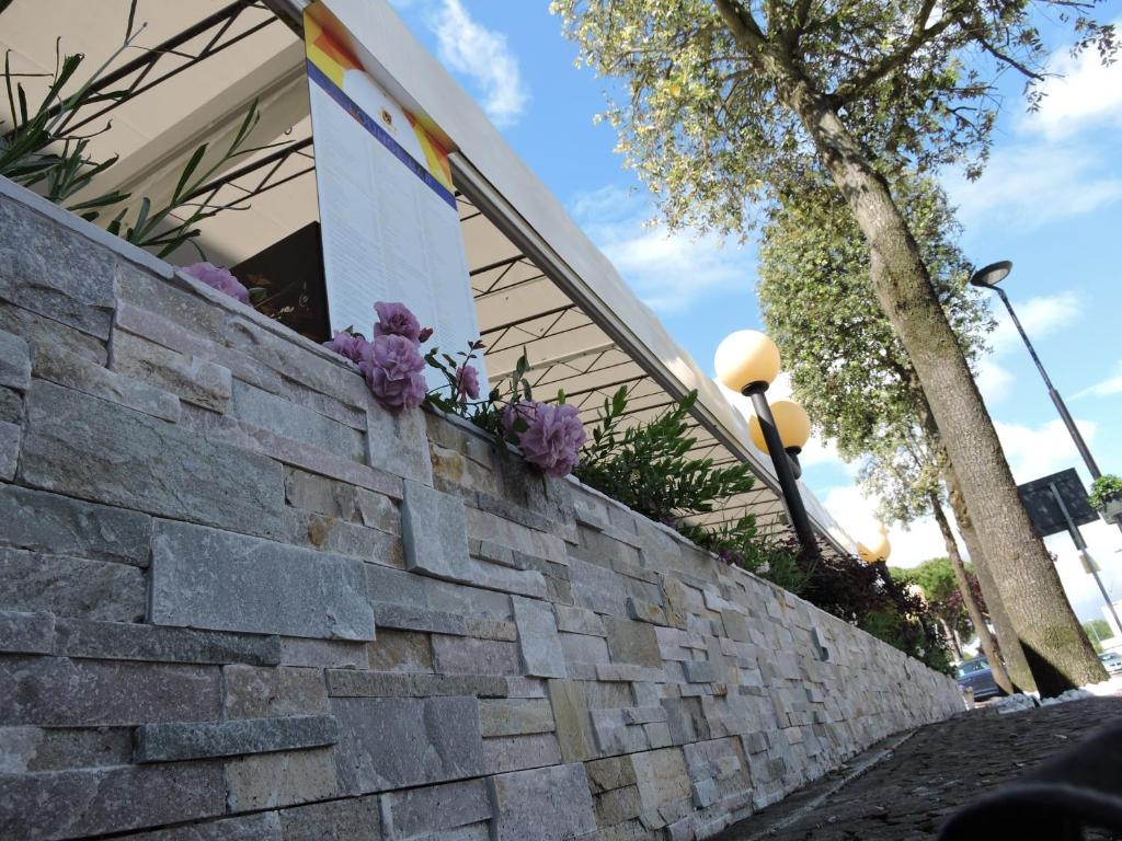 a stone retaining wall with purple flowers on it at Hotel Berna in Eraclea Mare