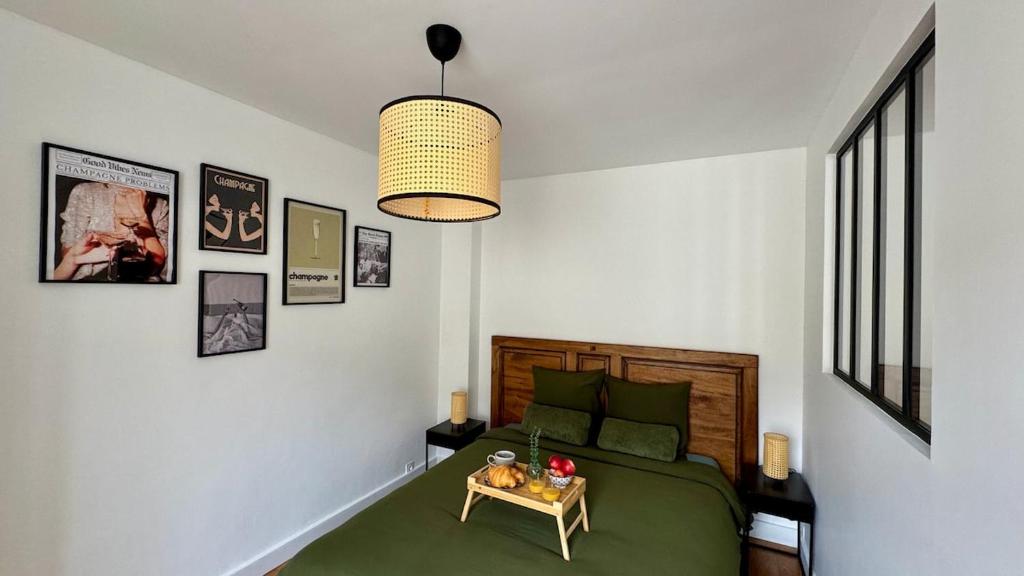a bedroom with a green bed and a table at La Bulle Millésimée - à deux pas de la Gare et de l'Avenue de Champagne in Épernay