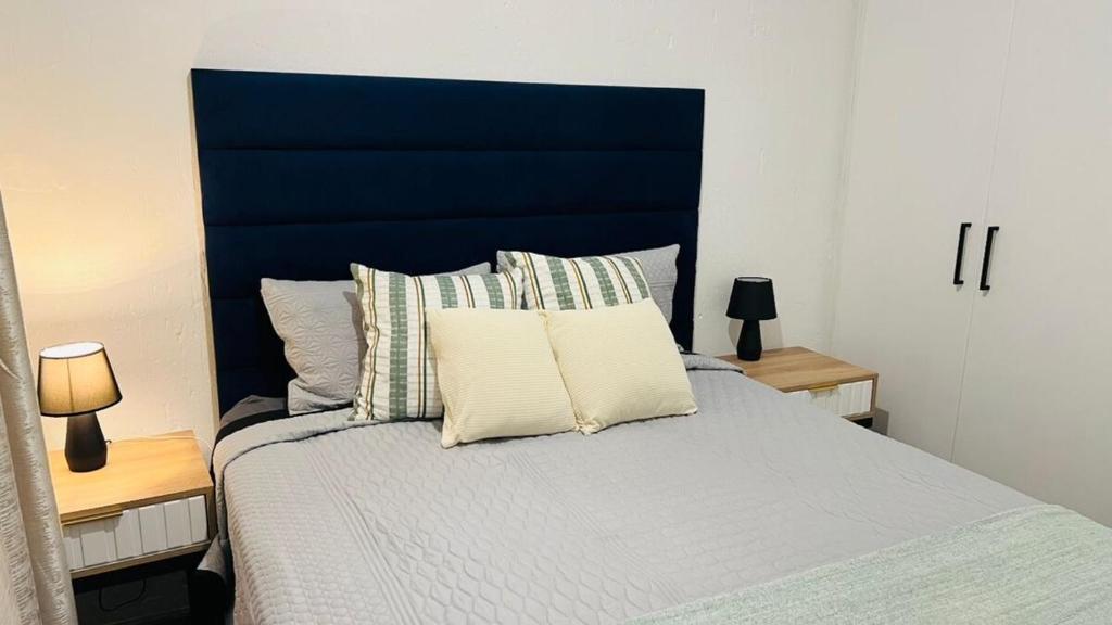 a bedroom with a blue headboard and a bed with pillows at Luxury Two-Story Loft - Beautiful Golf Course Views in Roodepoort