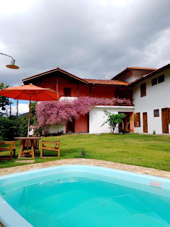 een huis met een zwembad en een tafel en een parasol bij Pousada Cipó Paraty in Paraty