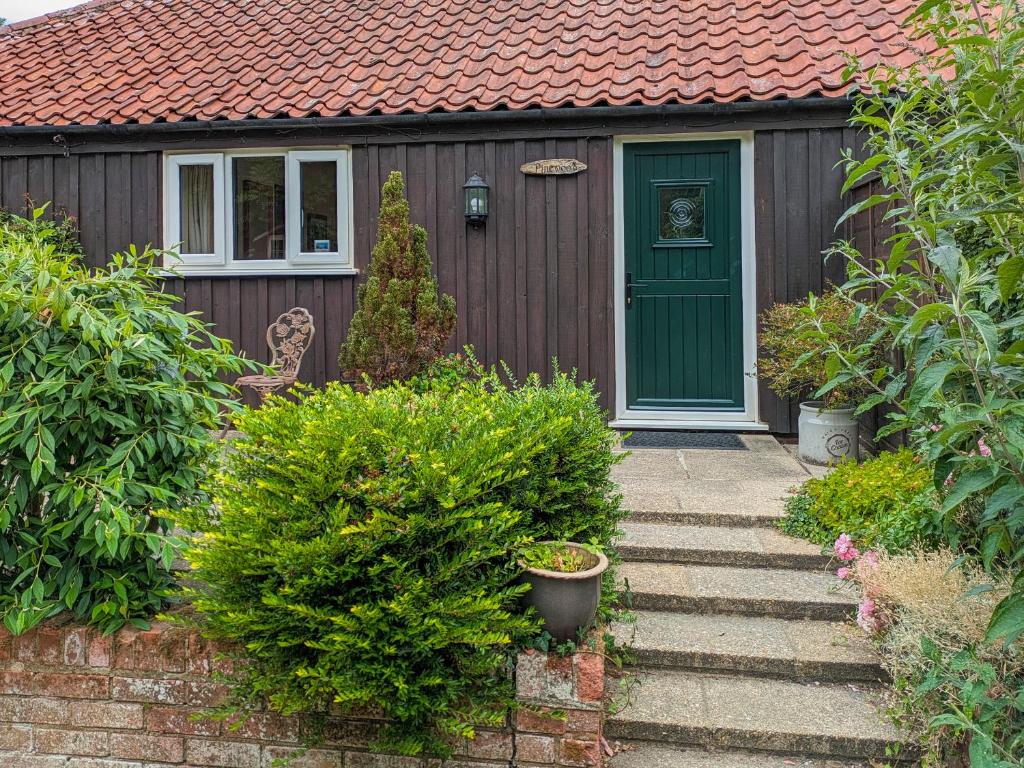 a house with a green door and some bushes at Pinewood - E3077 in Thorpe Market