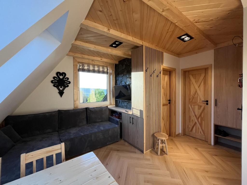 Una sala de estar con un sofá negro y una ventana. en Apartamenty pod Tatrami, en Zakopane