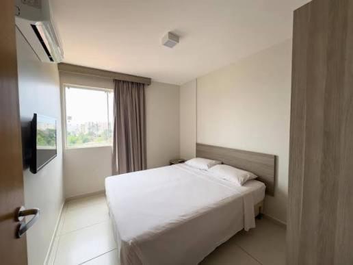a bedroom with a white bed and a window at Atrium Thermas Residence Service in Caldas Novas