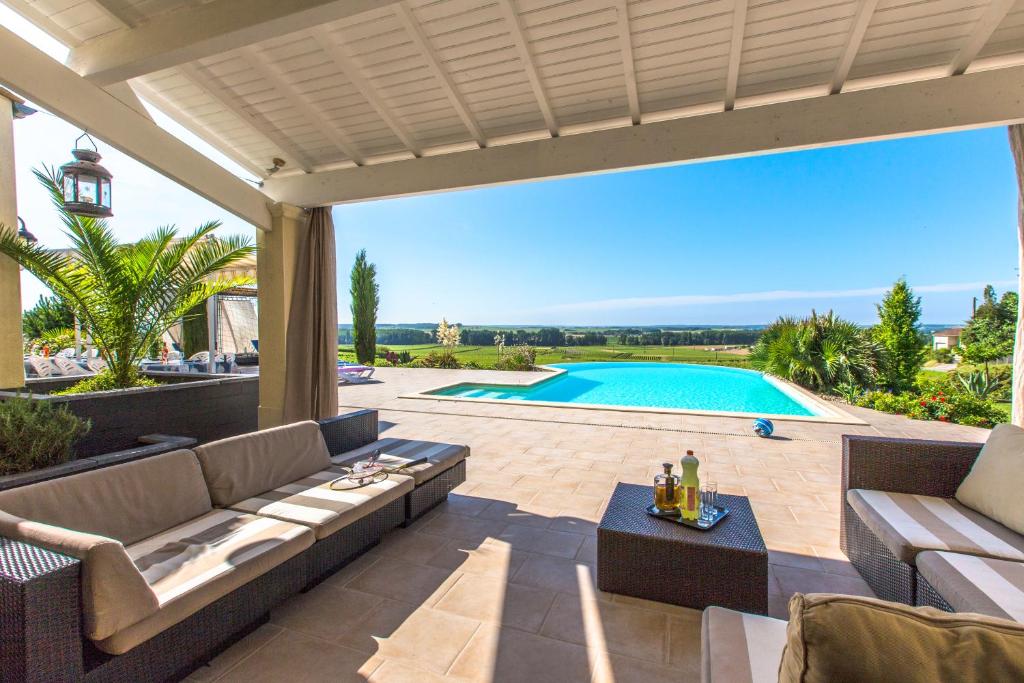 une terrasse avec un canapé et une table ainsi qu'une piscine dans l'établissement Villa Salena, à Sainte-Lheurine