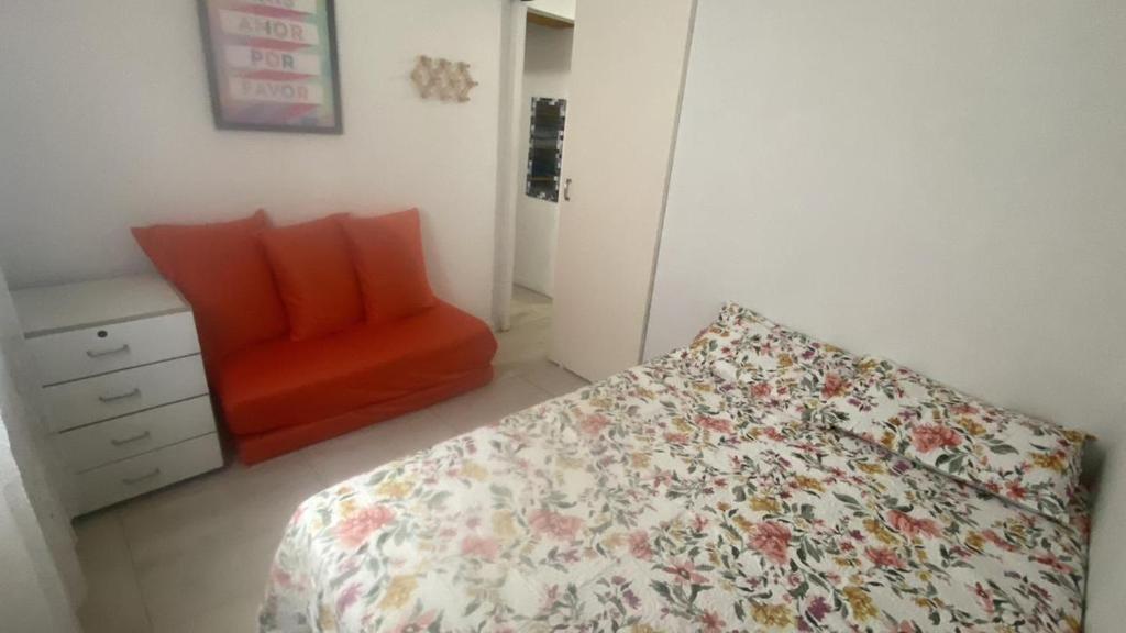 une chambre avec un lit et une chaise rouge dans l'établissement APTO 337 Malibu Praia Grande SP, à Praia Grande