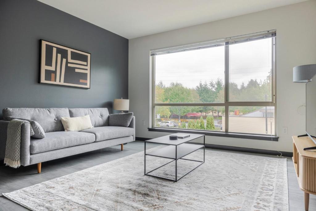ein Wohnzimmer mit Couch und großem Fenster in der Unterkunft Blueground Northeast Bellevue rooftop nr Lake SEA-909 in Highlands