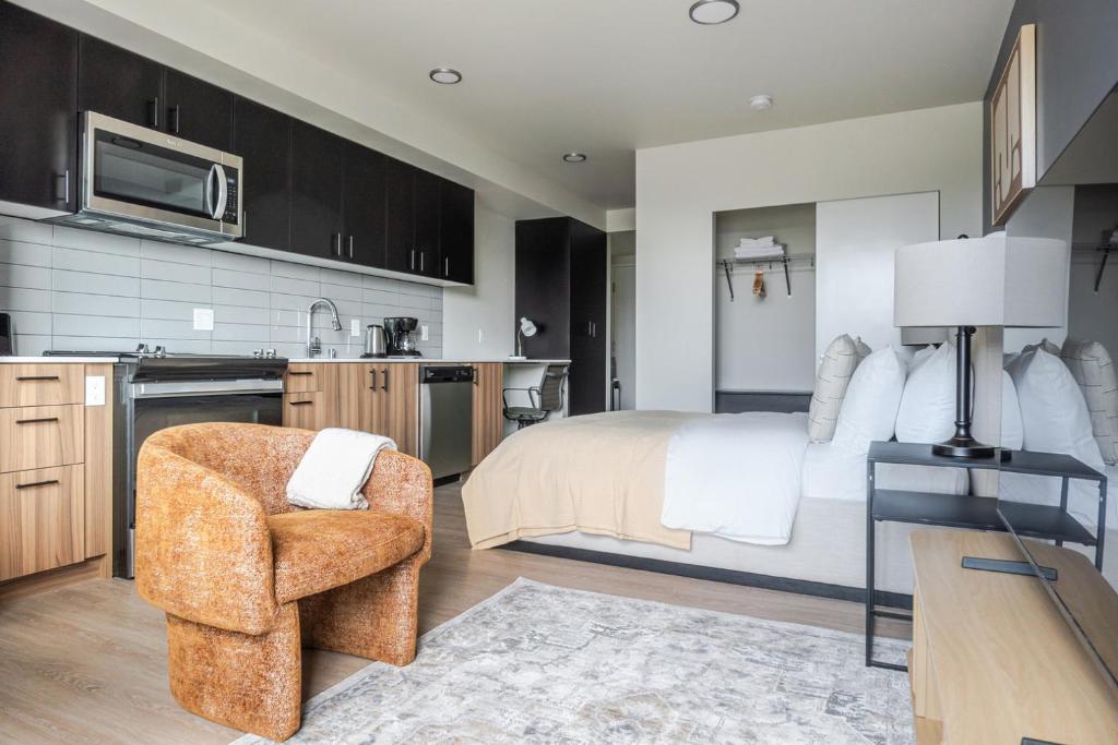 a bedroom with a bed and a chair and a kitchen at Blueground Meridian Park rooftop BBQ nr Park SEA-933 in Shoreline