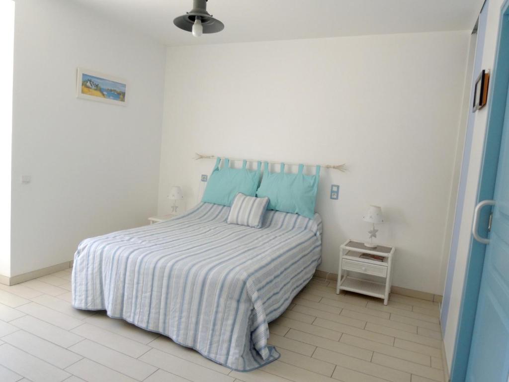 a white bedroom with a bed with blue pillows at Les Stiers in Chancé