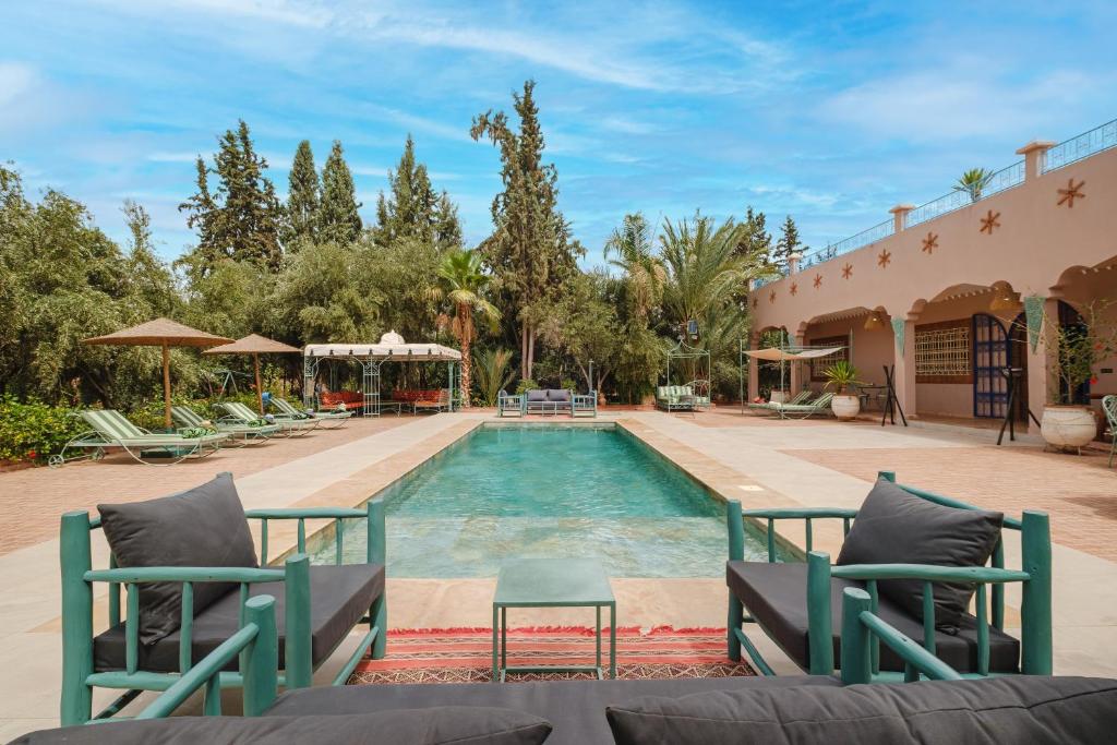 uma piscina num resort com cadeiras e árvores em Dar Salah - Eddine Oasis Pool & SPA em Marraquexe