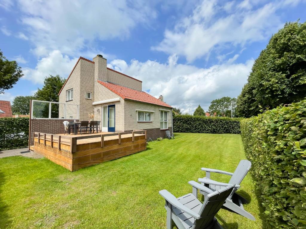 a yard with two lawn chairs and a house at Watervilla de IJsvogel by Droomvilla in Langweer