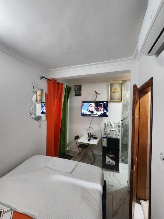Un dormitorio con una cama, un escritorio y un televisor. en Kerole's House, en Douala