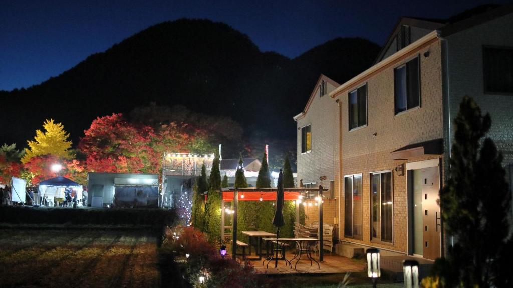 a building with a table and chairs at night at Cottage Pastorale in Fujikawaguchiko