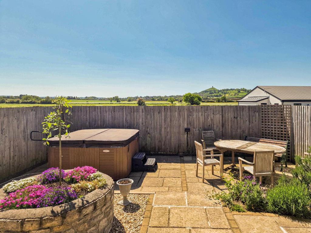 un patio con mesa y sillas y una valla de madera en The Dairy - Uk38051, en West Pennard