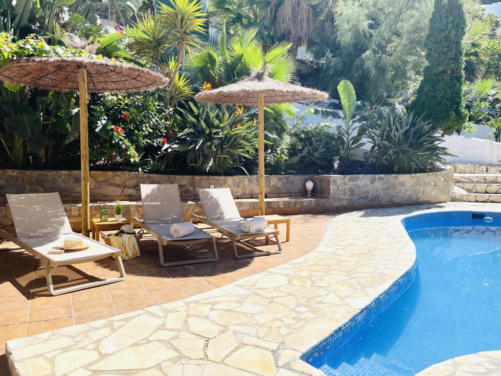 a swimming pool with two chairs and umbrellas next to a swimming pool at Villa Jina con piscina by At Home Costa del Sol in Torrox