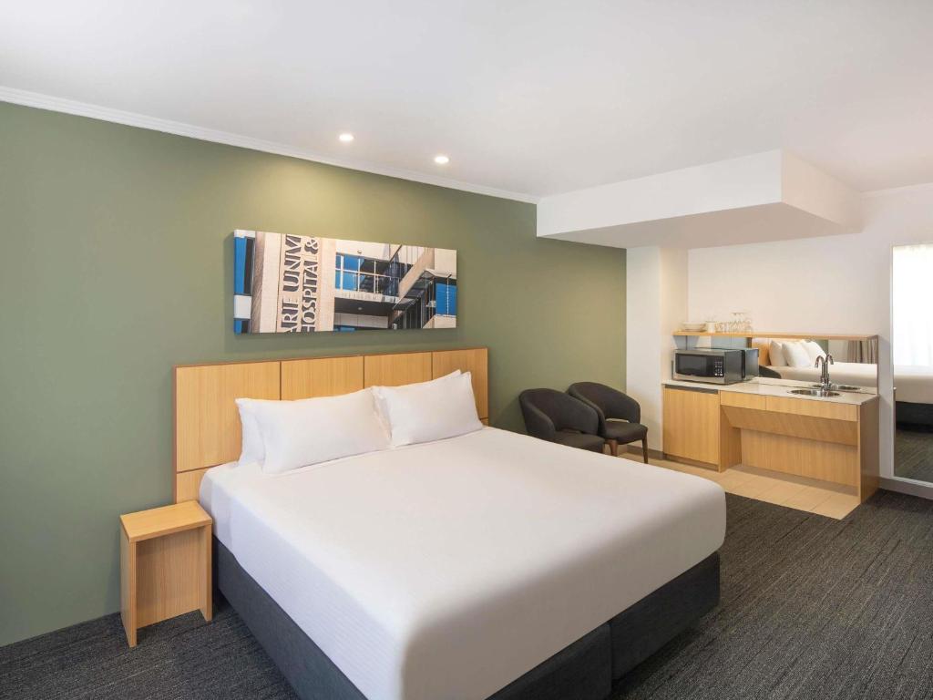 a hotel room with a bed and a kitchen at Mercure Sydney Macquarie Park in Sydney