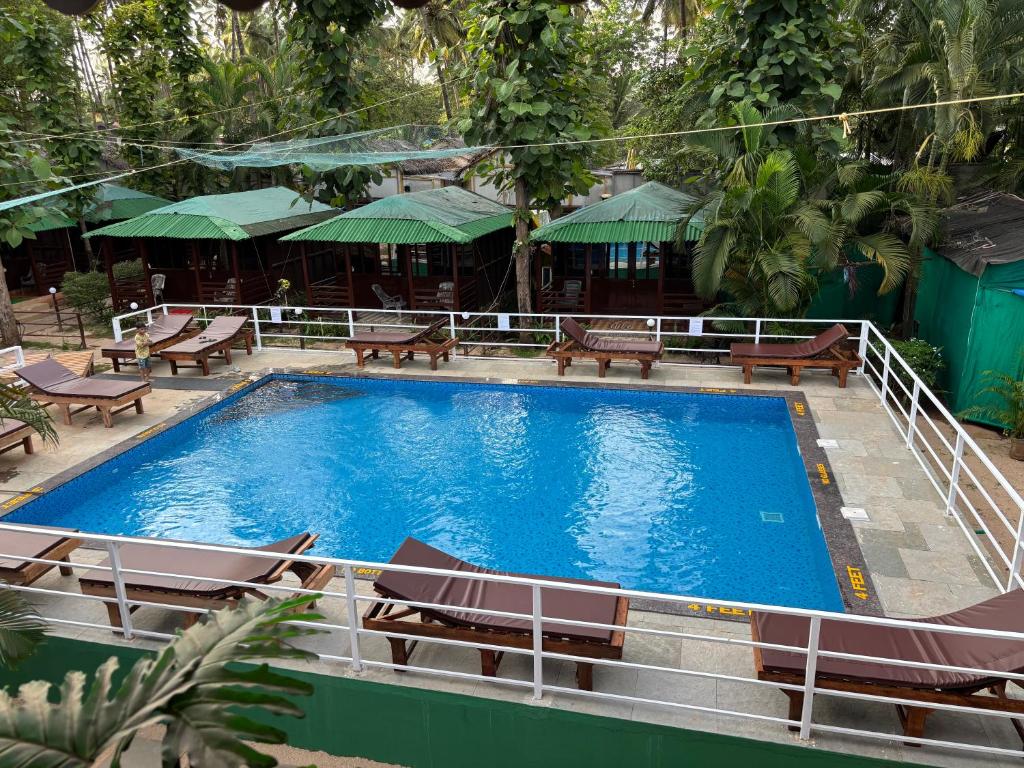 a large swimming pool with chairs and a hotel at Club Palolem Resort in Palolem