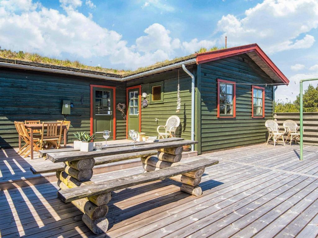 a green cabin with a wooden deck with a table at 6 person holiday home in Rømø in Bolilmark