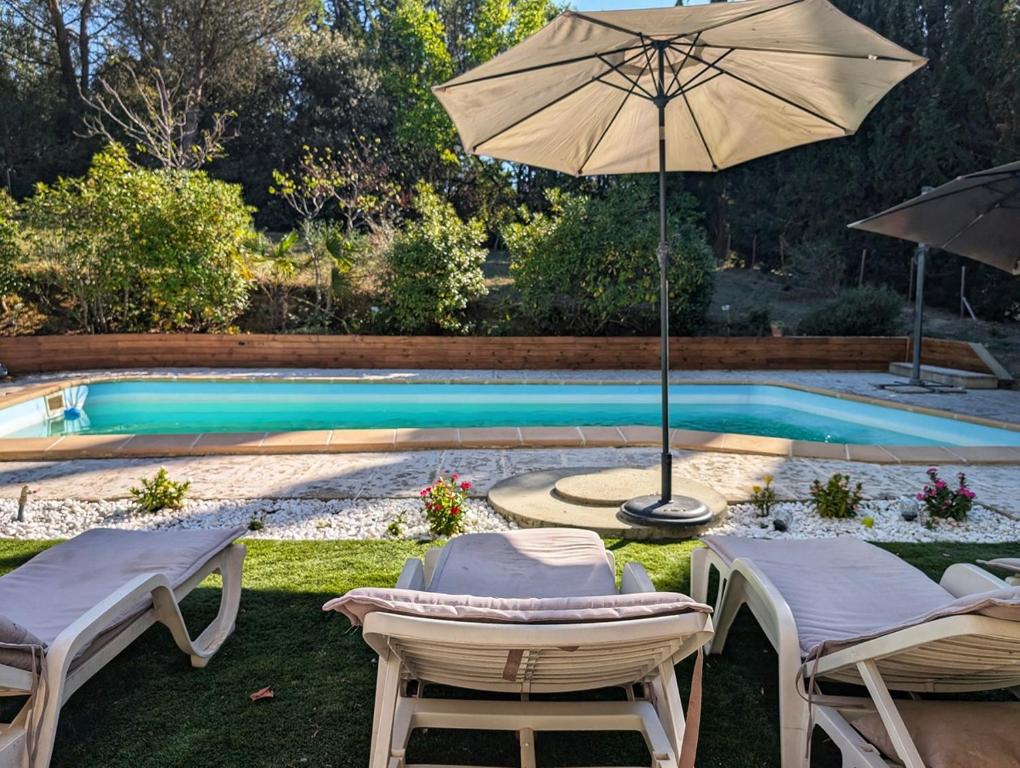 a swimming pool with two chairs and an umbrella at Eliane & Benjamin in Pezens
