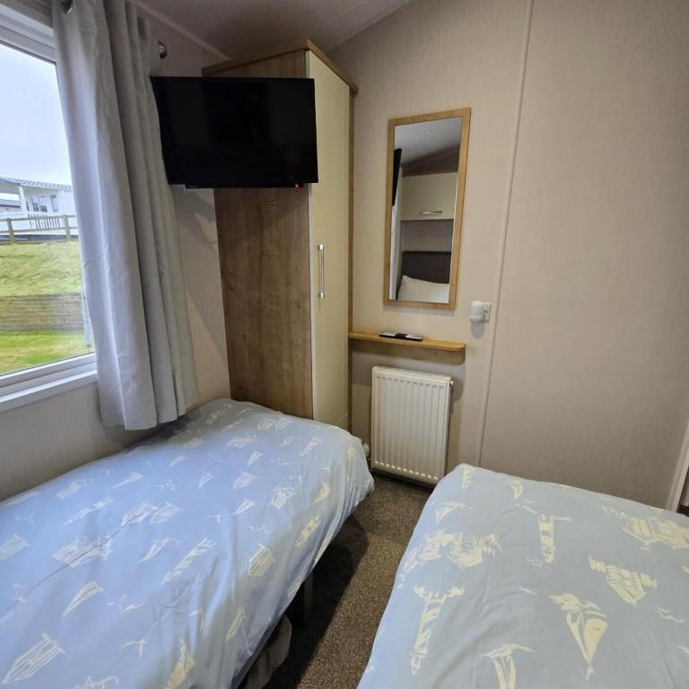 a bedroom with two beds and a flat screen tv at Thornwick Bay Holiday Village - Holiday Accommodation 20633 in Flamborough