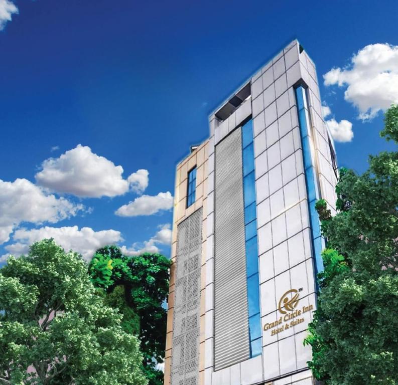 a building with trees in front of a blue sky at Hotel Grand Circle Inn in Dhaka