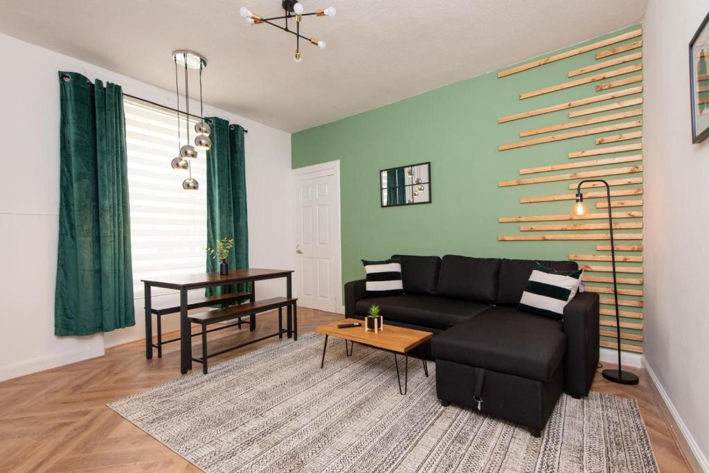 a living room with a black couch and a table at Northcote apartment in Hawick