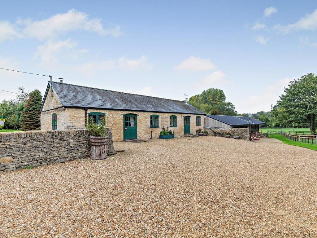 an old stone barn with a gravel driveway in front of it at 1 Bed in Bourton-on-the-Water 44960 in Withington