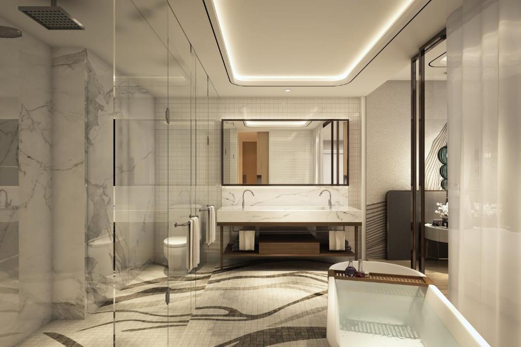 a bathroom with a tub and a sink and a mirror at voco Ma Belle Danang by IHG in Da Nang