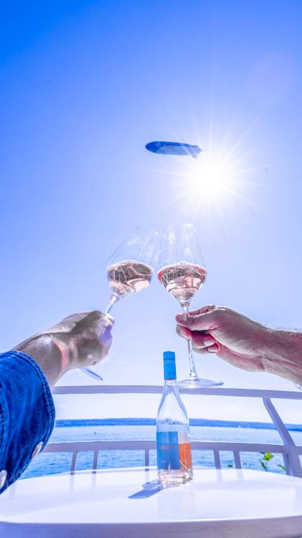 a person holding two wine glasses on a table at Seehotel ZUR MÜNZ in Meersburg