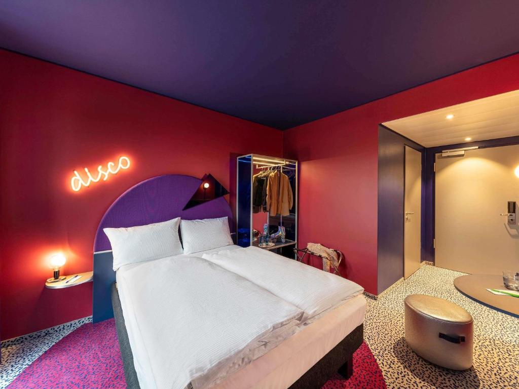 a bedroom with a large bed and a sign on the wall at ibis Styles Muenchen Perlach in Munich