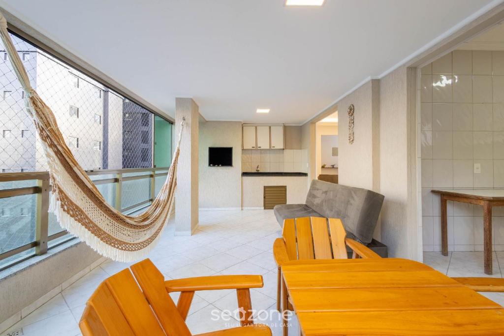 a living room with a hammock and a kitchen at Apto c/ varanda e churrasq. a 290m do mar CAU0199 in Meia Praia