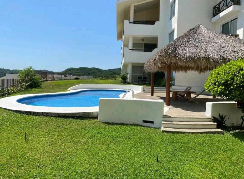 a swimming pool in a yard next to a building at Departamento Cruz de Mar in Santa Maria Huatulco