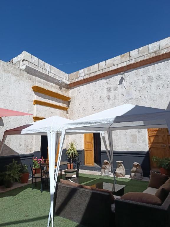 un patio avec un parasol blanc, une table et des chaises dans l'établissement Barrio Sureño Hotel Boutique, à Arequipa