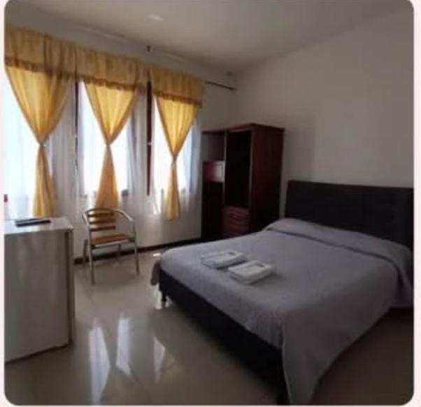 a bedroom with a bed and two windows at Hotel clásico in Manizales