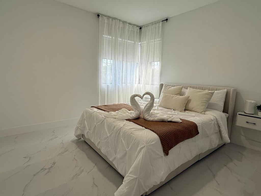 a white bedroom with two swans on a bed at Luxury apartment at excellent location, Breakfast and Parking in Miami
