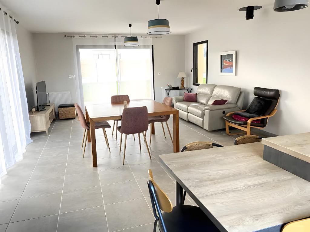 a living room with a couch and a table and chairs at Ty Cath - Maison en bord de mer in Guissény
