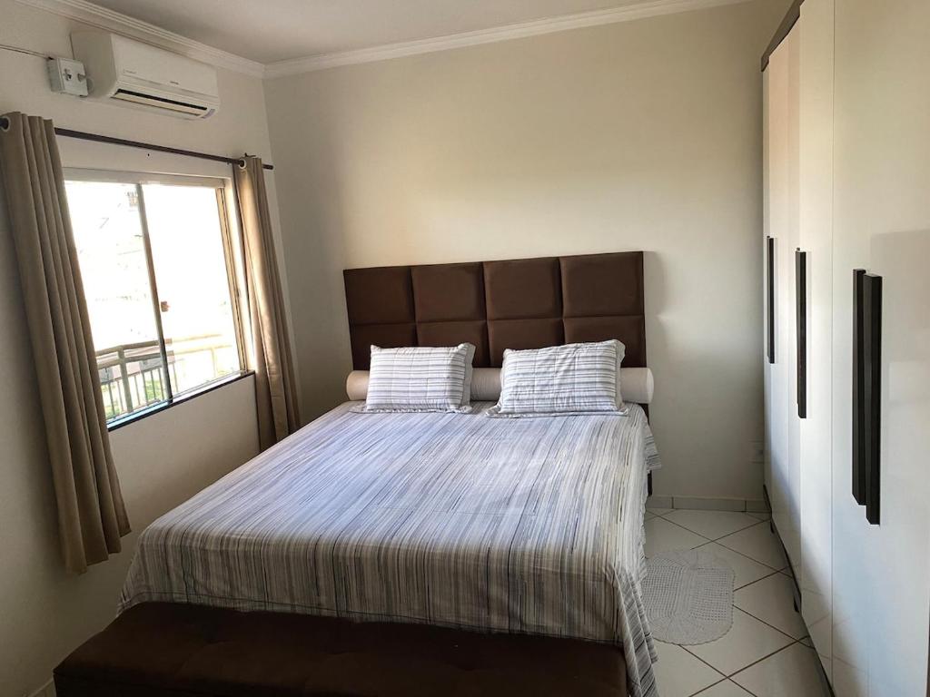 a bedroom with a bed with two pillows and a window at Apartamento 2 quartos in Caetité
