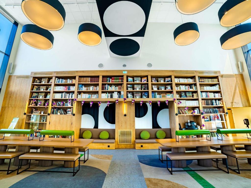 biblioteca con mesas, sillas y estanterías en ibis Styles La Roche-sur-Yon, en Mouilleron-le-Captif