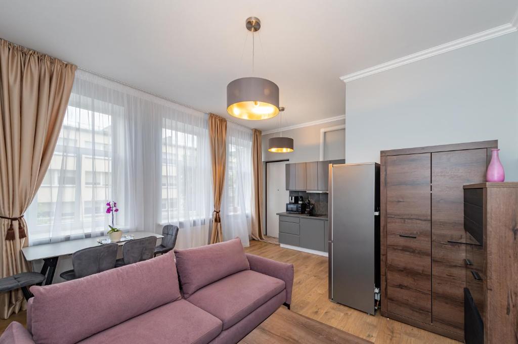 a living room with a couch and a table and a kitchen at Elegant city center apartment with free parking by Polo Aparments in Kaunas