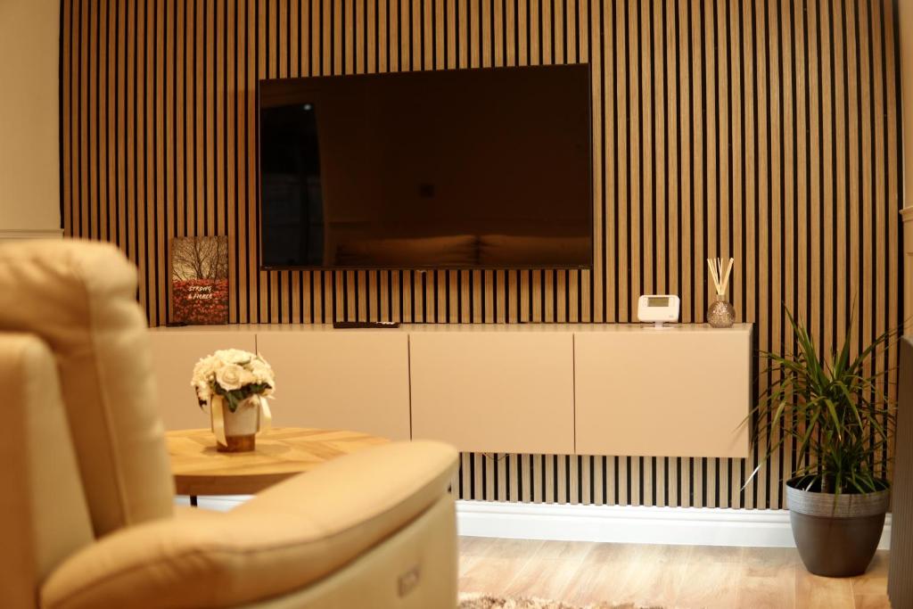 ein Wohnzimmer mit einem TV und einem Tisch mit einem Stuhl in der Unterkunft Modern, Spacious Home Near Manchester - Perfect for Families group in Hollinwood