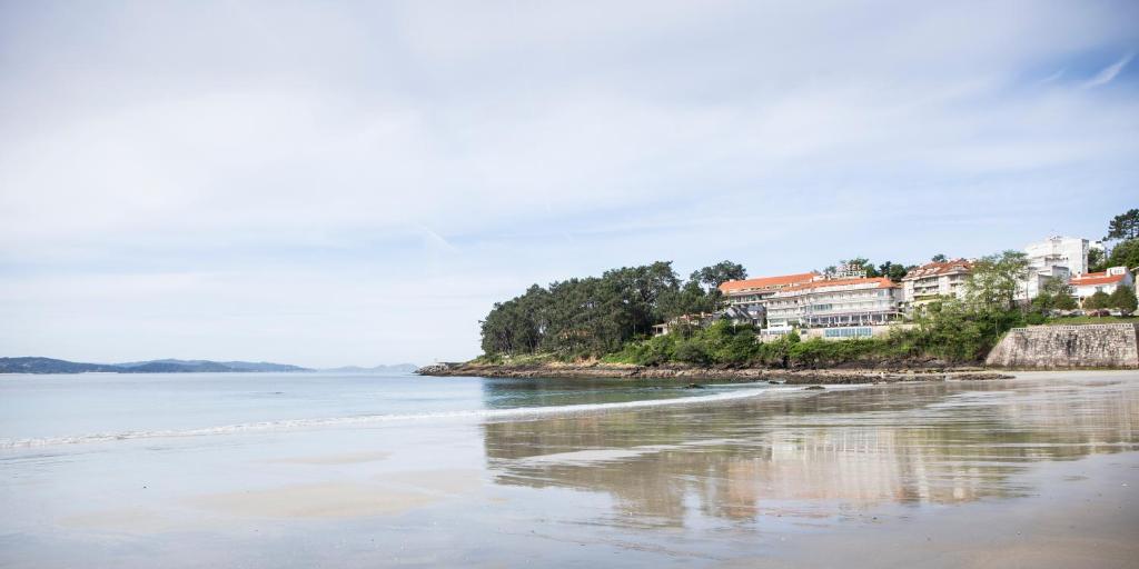 Gran Talaso Hotel Sanxenxo في سانكسينكسو: اطلالة على شاطئ به بيوت على الشاطئ