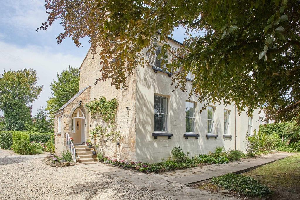a white building with a door and a tree at Host & Stay - Thorneville House in Knaresborough